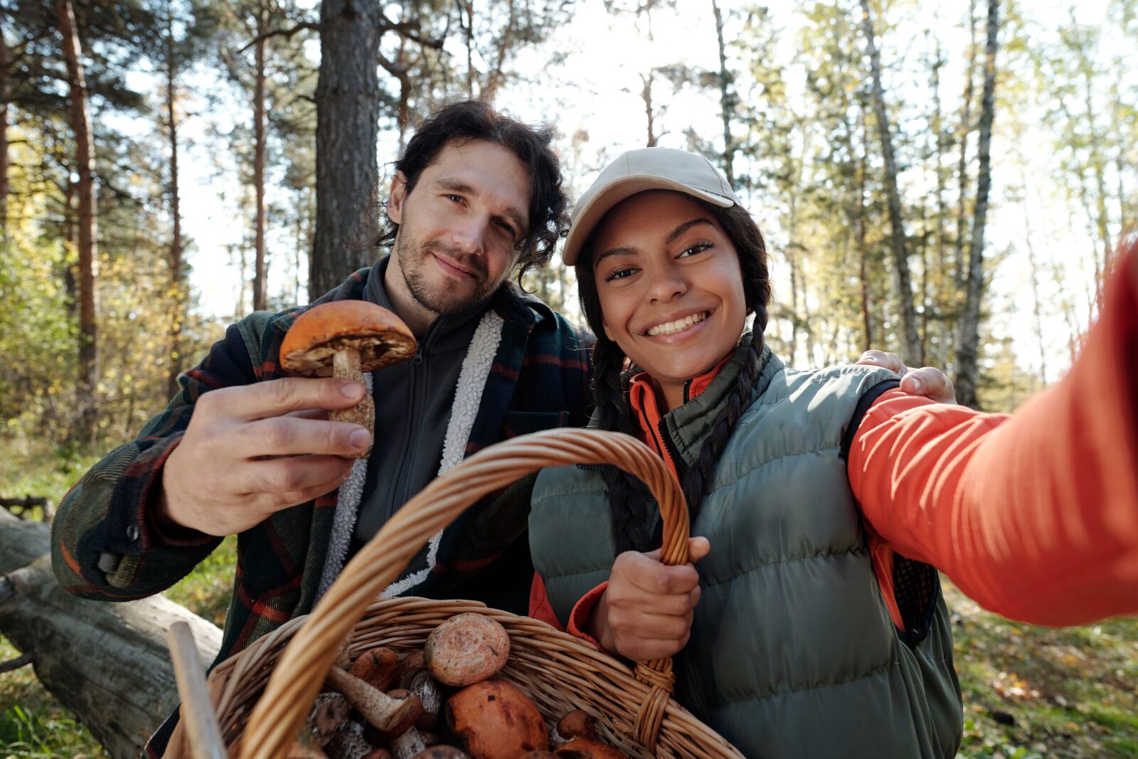 Couple holding a basket of freshly foraged wild mushrooms in a forest